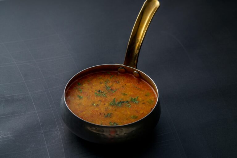 A close-up shot of Indian dal garnished with herbs in a copper pot, offering a taste of traditional cuisine.